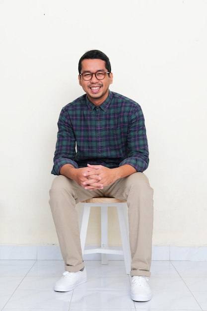 Asian man sitting relax in a bench while smiling to camera