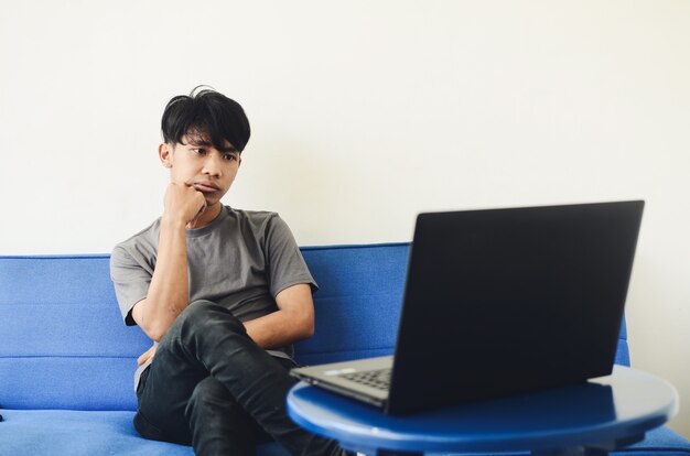 Asian man sitting sofa disappointed expression