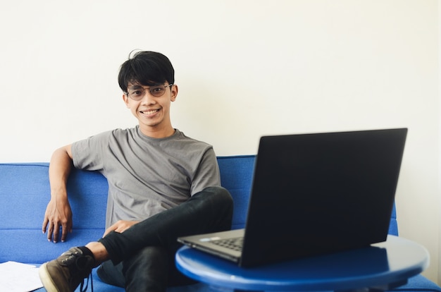 Asian man sitting on the sofa with a cheerful expression