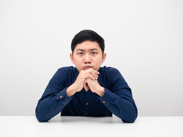 Asian man sitting at the table feeling worry about something and looking at you serious face