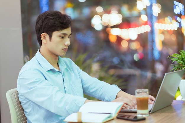 Asian man sitting working alone at a coffee shop