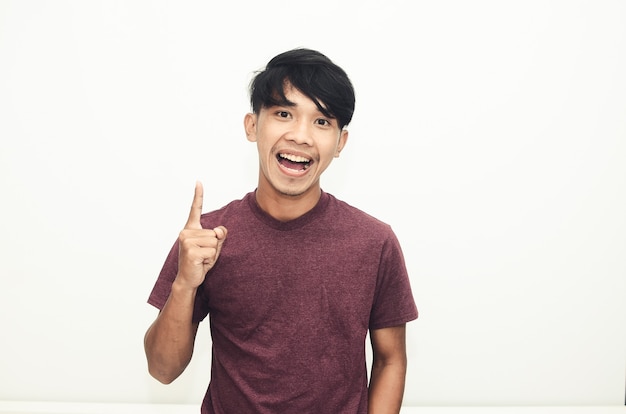 Asian man smiling in casual t-shirt while pointing at empty space
