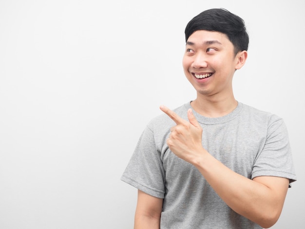 Asian man smiling grey shirt point finger at copy space