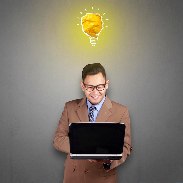 Asian man smiling happy with bright light bulb lamp made of paper symbol of idea and innovation