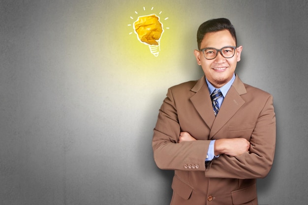 Asian man smiling happy with bright light bulb lamp made of paper symbol of idea and innovation