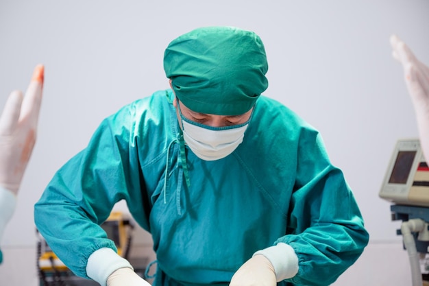 Asian man specialist surgeon in uniform operating patient and hand colleagues in operating room