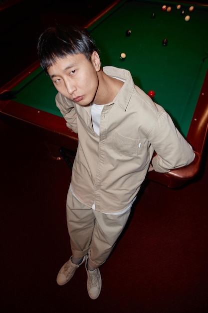 Photo asian man standing by pool table with flash