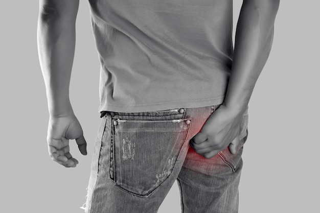 Asian man standing scratching his ass on a gray background