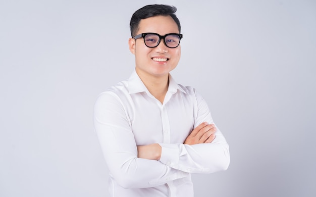 Asian man standing with folded arms on gray