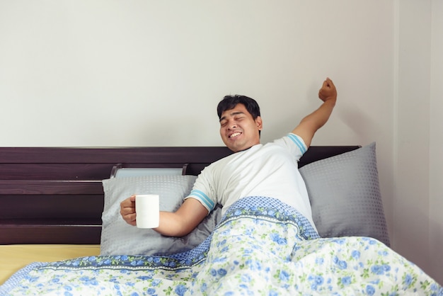 Asian man stretching and drinking coffee in morning time