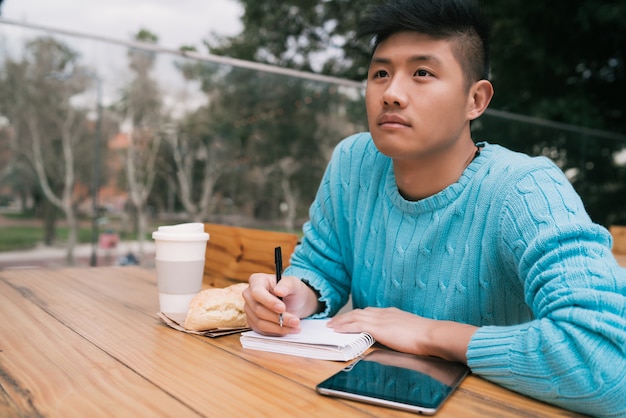 Uomo asiatico che studia nella caffetteria