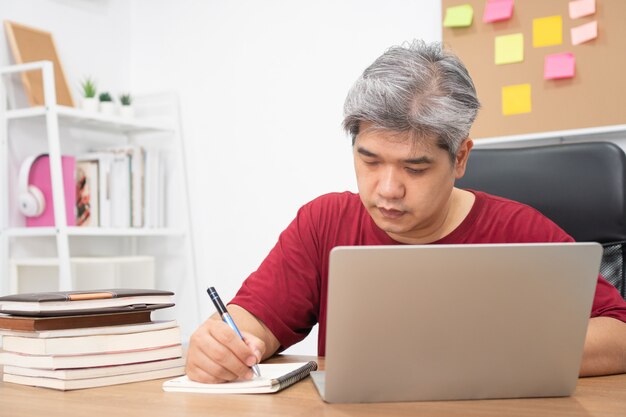 Uomo asiatico che studia per le nuove abilità da internet a casa