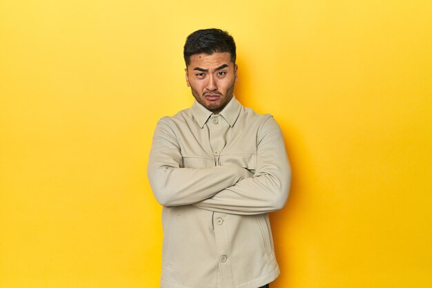 Asian man in stylish gray shirt on yellow studio unhappy looking in camera with sarcastic expression