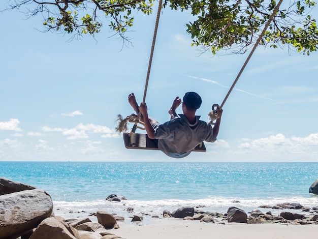 Asian man on swing at summer beach