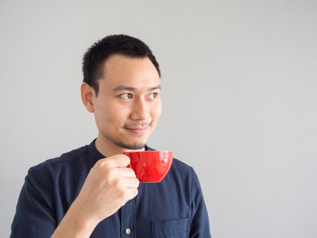 Asian man take a sip of coffee in red cup.