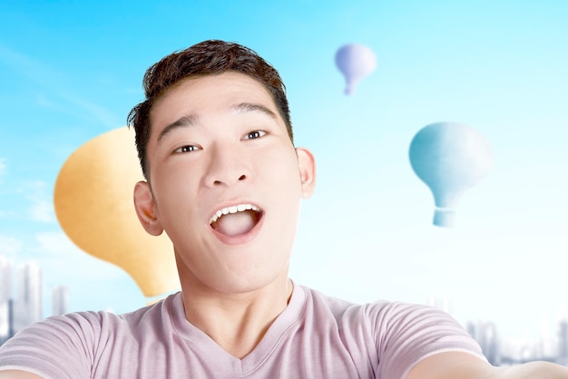 Uomo asiatico che si fa un selfie con una mongolfiera colorata che vola con lo sfondo del paesaggio urbano