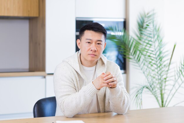 asian man talking online on video call at home in living room or kitchen