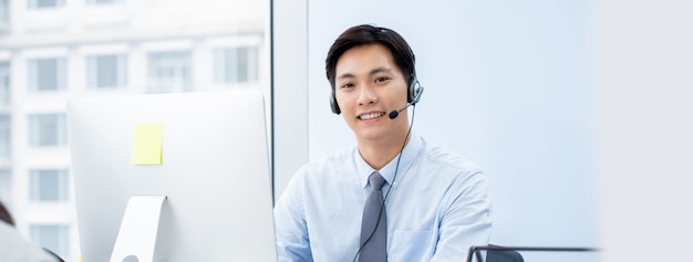 Агент телемаркетинга азиатского человека в офисе центра телефонного обслуживания