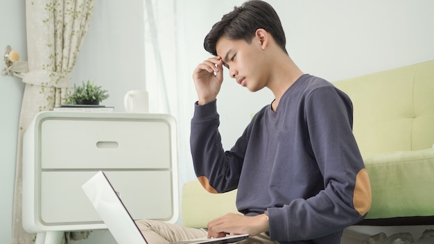 Asian man thinking image on his laptop screen at home