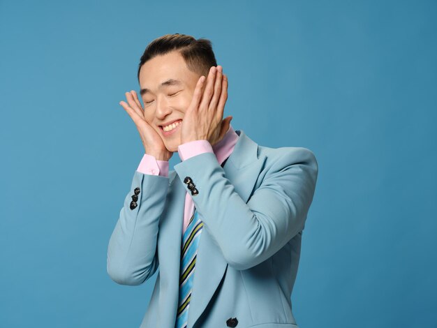 Uomo asiatico che si tocca il viso con le mani su sfondo blu