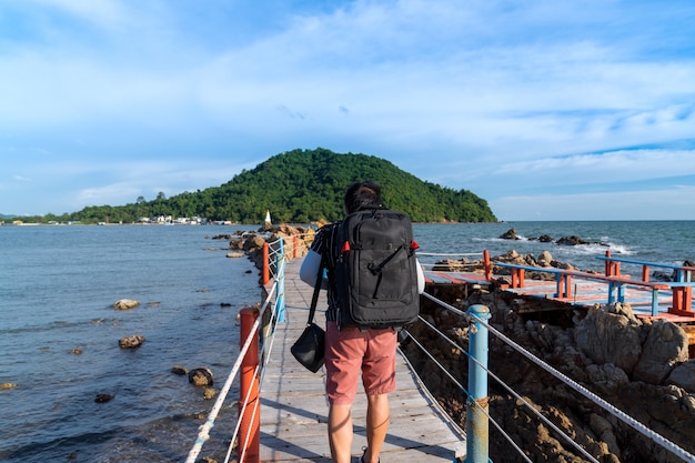 Photo asian man tourist backpaker walking on wooden bridge with rope rail bridge viewpoint to see pagoda