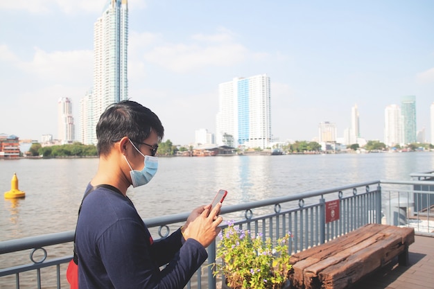 사진 방콕 여행 위치에서 휴대 전화를 사용하여 얼굴 마스크를 쓰고 아시아 남자 관광