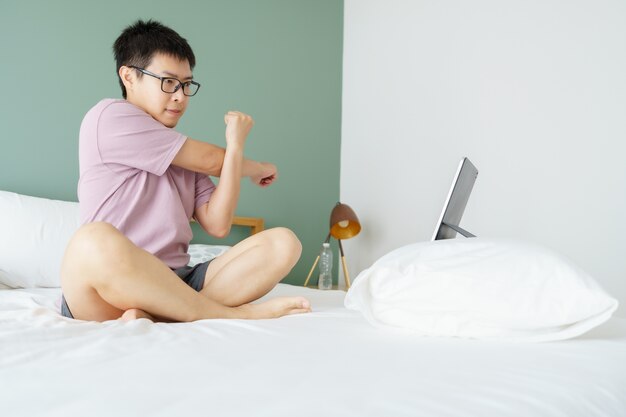 Азиатский мужчина тренируется дома, смотрит видео на планшете