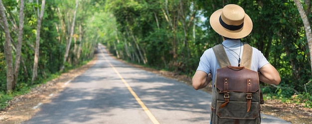 アジア人男性旅行と森の風景の背景の道を歩くタイで春の季節の旅行の概念