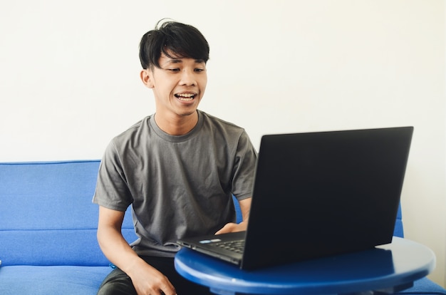 Photo asian man typing and sitting on the sofa