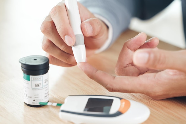 Asian man using lancet on finger for checking blood sugar level by Glucose meter