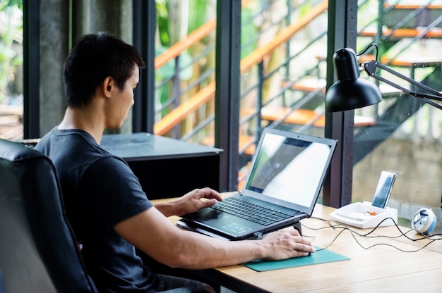 Uomo asiatico che utilizza un computer portatile nella stanza.