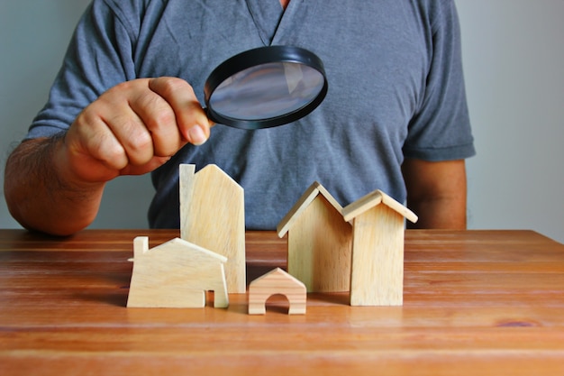 Photo asian man using magnifying looking to wood model home