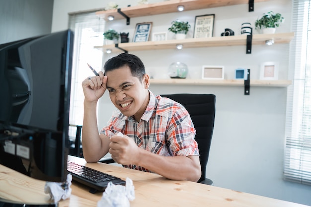 Asian man waiting for something looking at pc