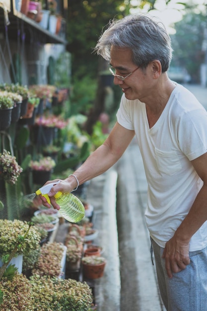 Фото Азиатский мужчина поливает домашнее растение в домашнем саду