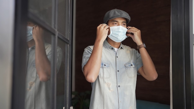 L'uomo asiatico indossa una maschera prima di aprire il suo negozio di affari