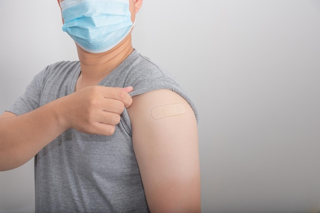 Asian man wear mask showing arm getting COVID vaccination