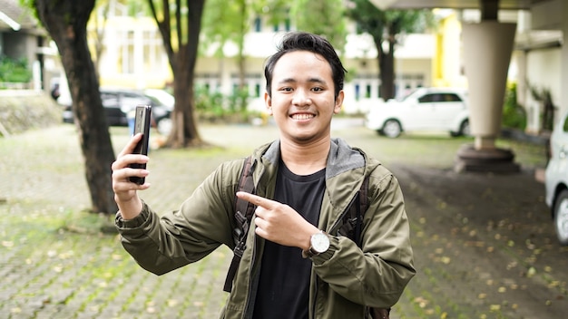 Asian man wearing a bag pointing the phone