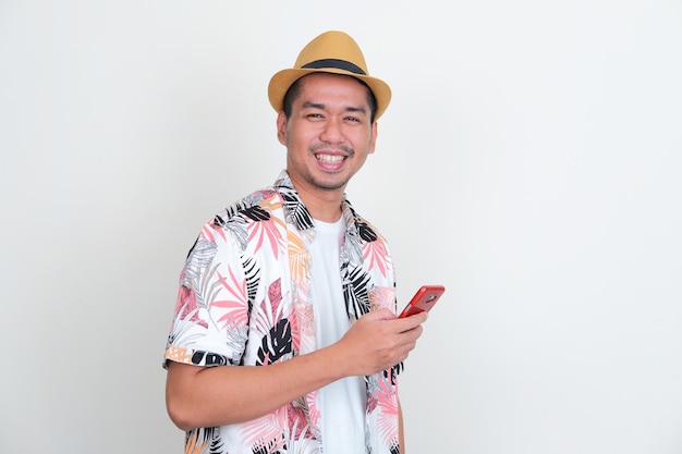 Asian man wearing beach shirt smiling happy while holding mobile phone