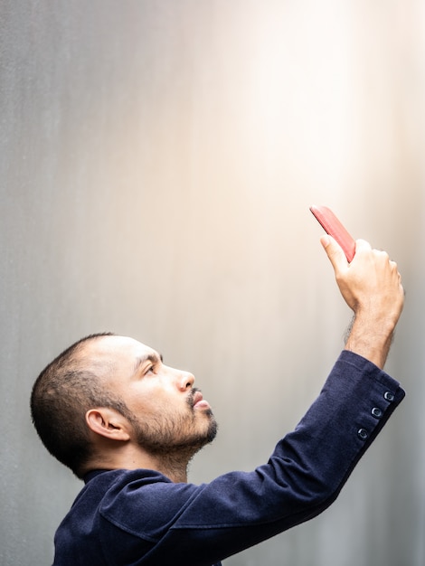 Photo asian man wearing blue suit raise his hand while holding smartphone.