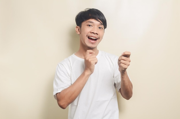 Asian man wearing bright white tshirt with gesture playing drums on isolated background