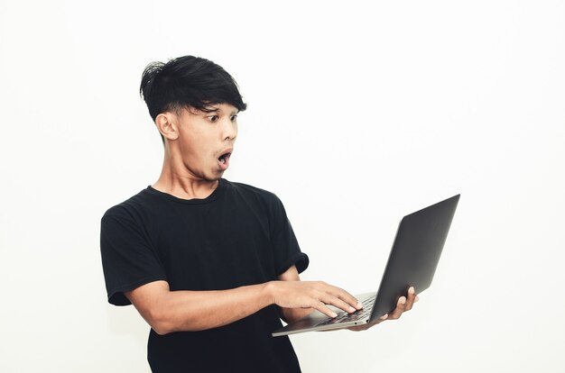 Asian man wearing a casual black shirt carrying a laptop with a shocked expression