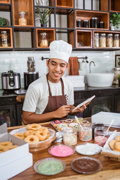 Asian man wearing a chef hat while sitting in the kitchen room