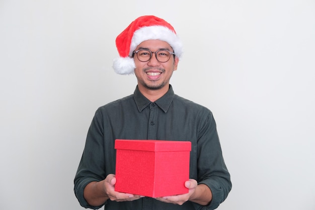 Asian man wearing Christmas hat holding a box of gift with happy expression