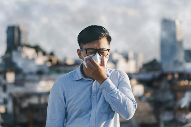 Uomo asiatico che indossa la maschera facciale per proteggere la polvere pm 25 e lo smog della polvere problema di inquinamento atmosferico