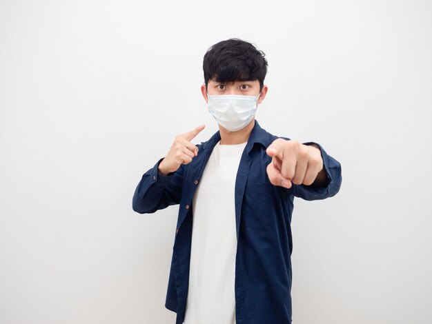 Asian man wearing mask serius face point finger athis face and point at you white background