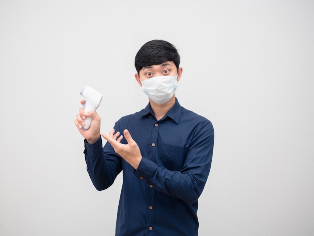 マスクを身に着けているアジア人男性は、スキャンポートレート白い背景のために彼の手に赤外線温度計を提案します