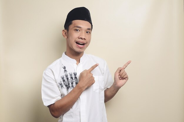 Asian man wearing muslim clothes pointing to empty space