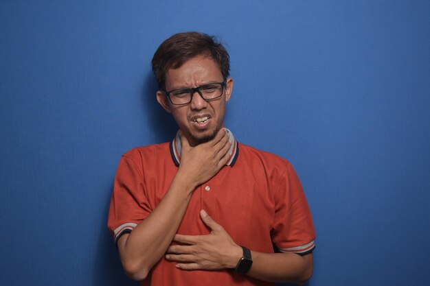 Photo asian man wearing orange casual tshirt touching painful neck sore throat for flu clod and infection