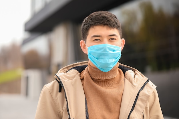 도시 거리에 보호 마스크를 착용하는 아시아 남자. 전염병의 개념