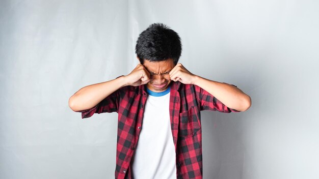 Photo asian man wearing red flannel tshirt cry using a tissue isolated white background